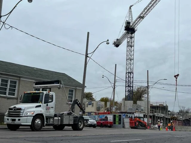 Crane loading debris into dumpster bin